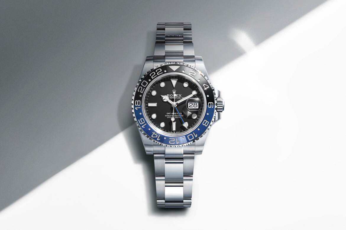 Rolex GMT‑Master II m126710BLNR‑0003 shown as the cover image, set against a diagonally divided dark‑grey and white backdrop representing night and day, echoing the watch’s dual‑time functionality