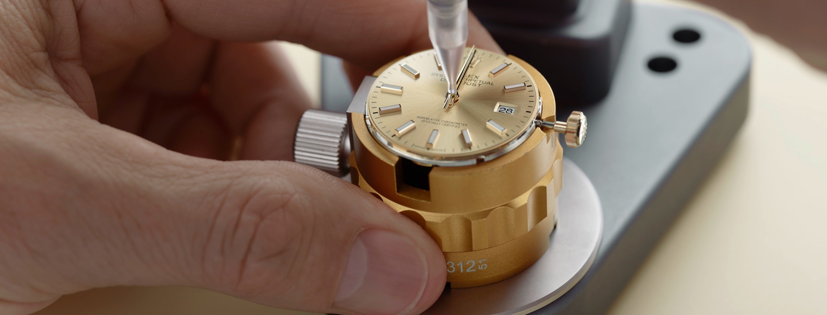 Close‑up image of a watchmaker carefully positioning the watch hands onto the dial using precision tools
