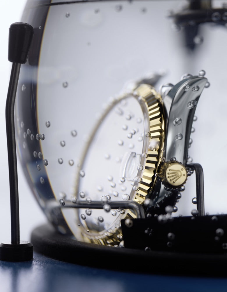 Close‑up of a Rolex watch fully submerged in water as part of its waterproofness testing process