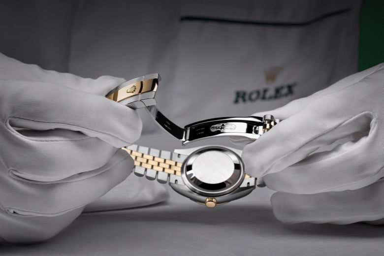 Close‑up image of a watchmaker holding a watch with both hands, carefully inspecting the clasp for proper function
