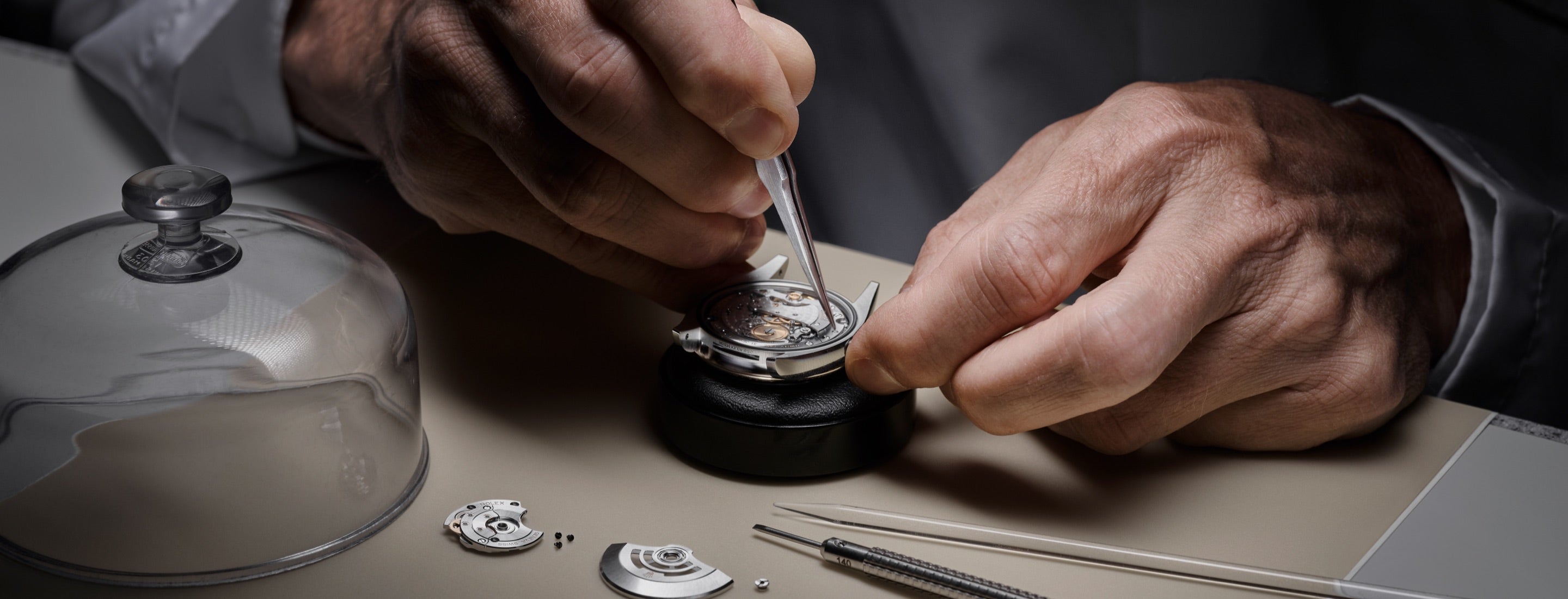 Close‑up image of a watchmaker meticulously dismantling a watch movement, preparing each component for careful inspection