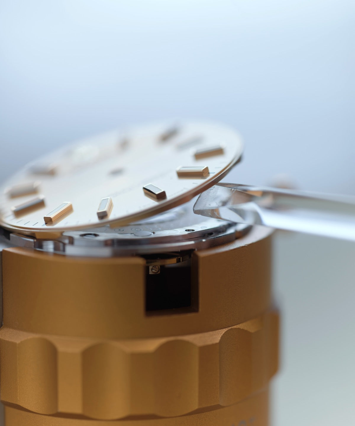 Detailed close‑up showing a watchmaker removing the dial from the movement, highlighting meticulous handling and expert craftsmanship