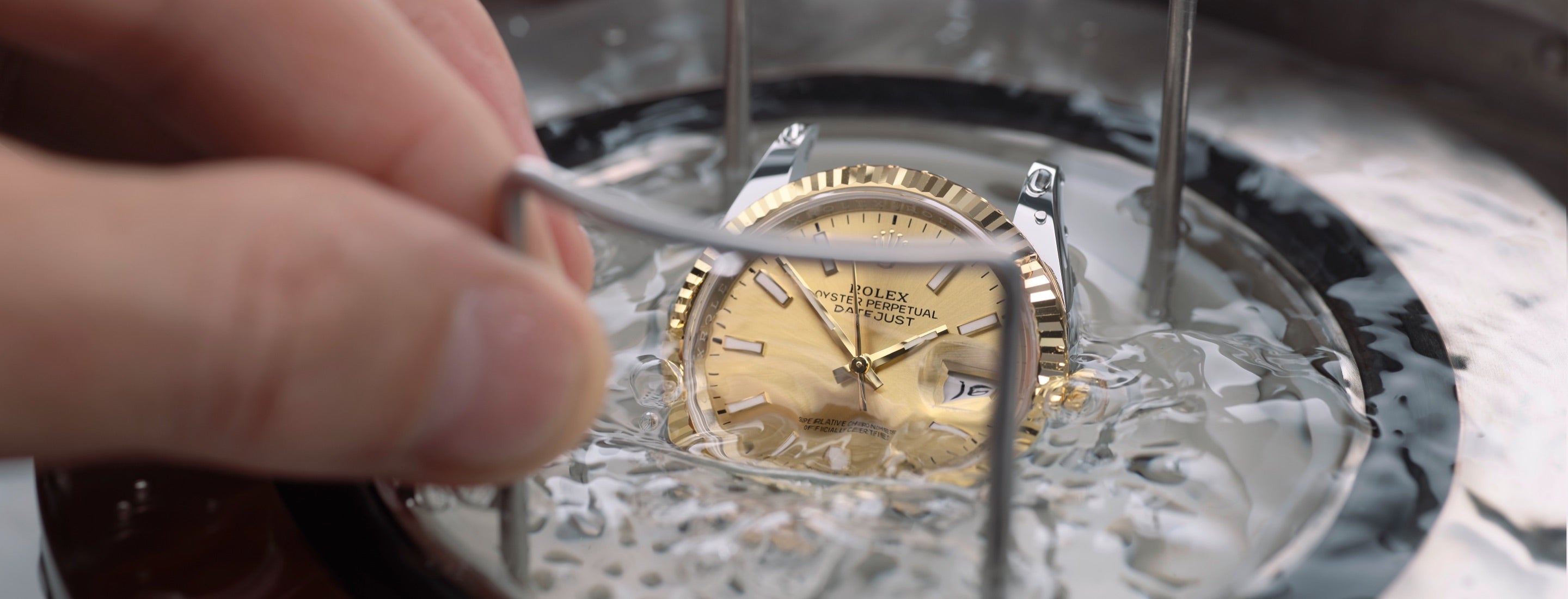 Close‑up view of a Rolex Datejust during a waterproofness test, showing the watch partially immersed as its sealing integrity is checked