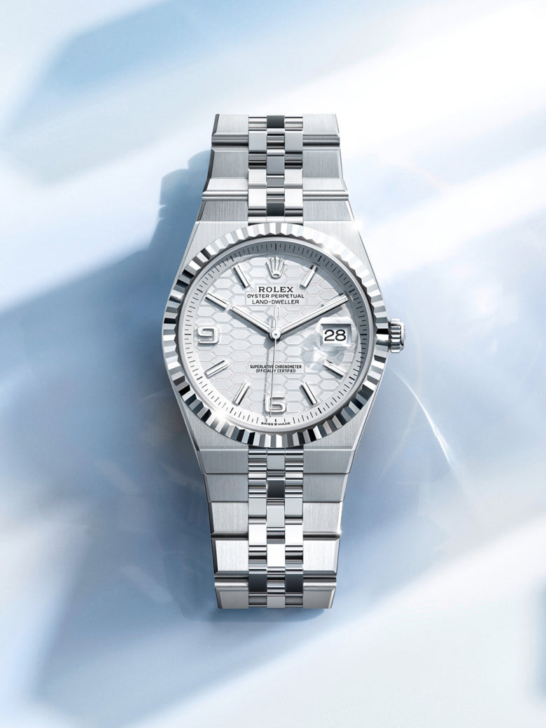 A call‑to‑action image for the Rolex Land‑Dweller m127234‑0001, featuring the watch displayed against a clean white background with soft shadows and crisp highlights that emphasise the refined contrast of its fluted bezel, Jubilee bracelet, and polished surfaces, creating a bright, elegant, and inviting visual that draws attention to the model’s distinctive design