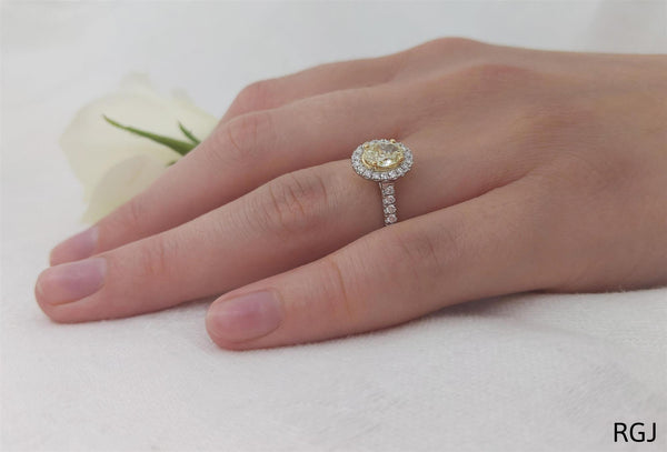 the skye platinum and 18ct yellow gold 0.71ct oval cut yellow diamond ring with 0.33ct diamond halo and diamond set shoulders model hand shot