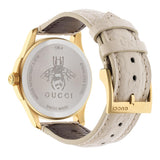 gucci g-timeless 38mm signature white dial gold PVD stainless steel watch on white leather strap back side facing upright image